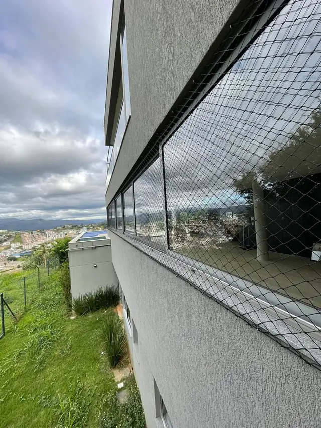 Fachada de casa com rede de proteção instalada em janelas e varanda