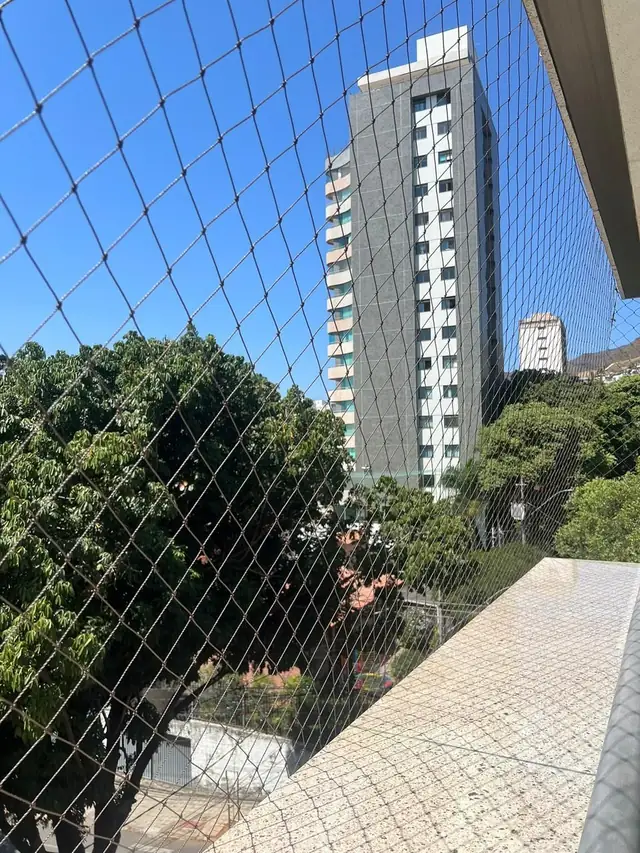 Rede de proteção preta em varanda com vista para prédio vizinho